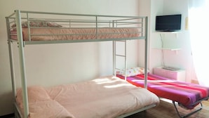 Habitación con literas, un televisor en la pared y una pequeña mesa con una lámpara.