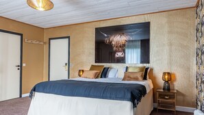 A bedroom with a large bed, a mounted TV, and a bedside table with a lamp. - Achouffe Valley (Houffalize)