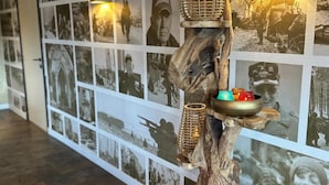 A wall with black and white photographs, a wooden sculpture with a bowl and candles, and two wall-mounted lights. - Achouffe Valley (Houffalize)