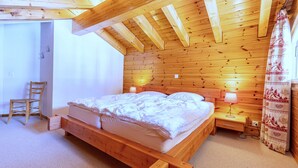 A wooden bedroom with a bed, bedside tables, a chair, and a window with curtains. - Stunning Apartment With Mountain Views (Veysonnaz)
