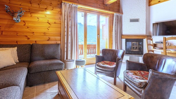 A cozy cabin interior with a wooden ceiling, a sofa, two chairs, a small table, and a fireplace. - Stunning Apartment With Mountain Views (Veysonnaz)
