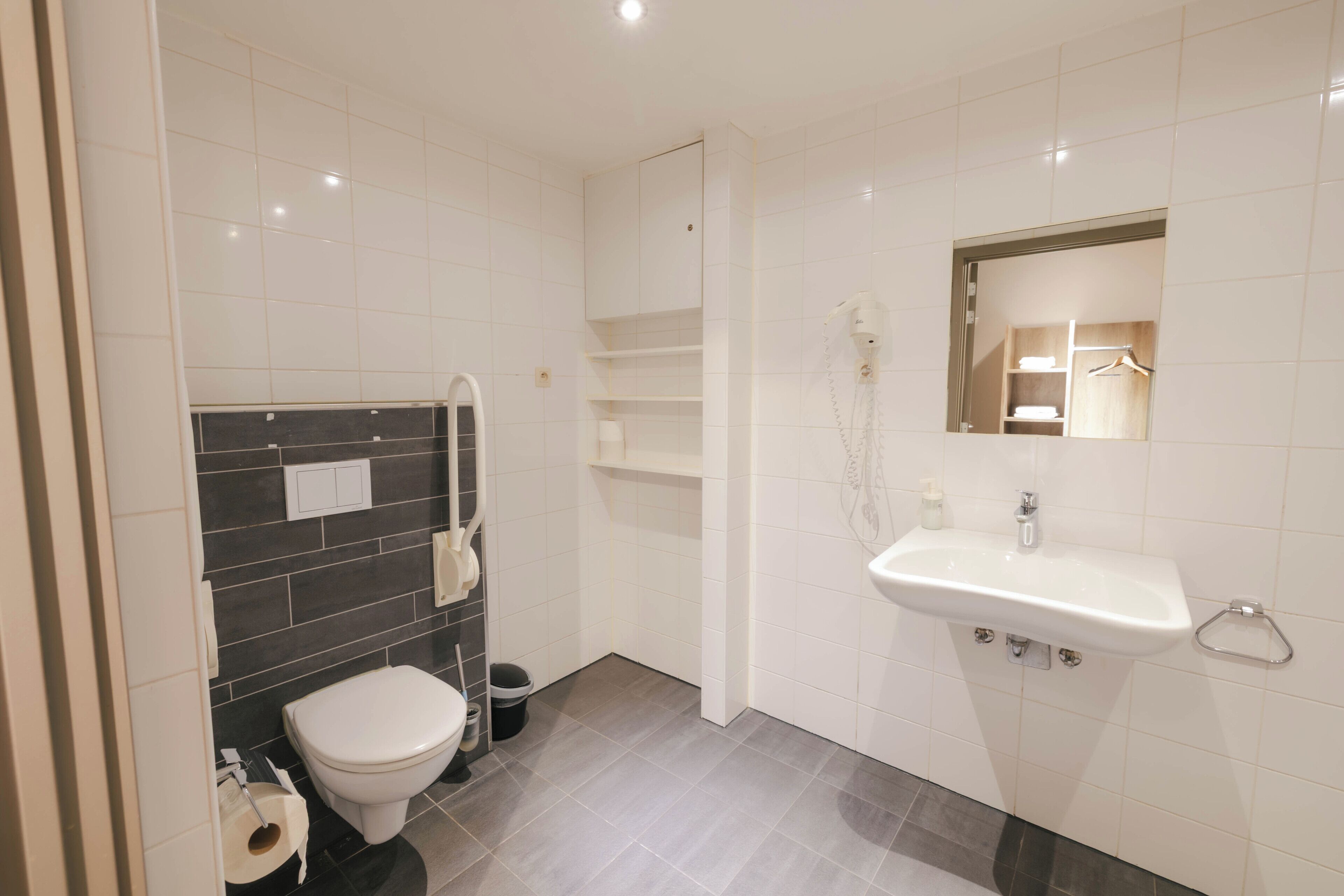 A modern bathroom with a toilet, sink, and mirror.
