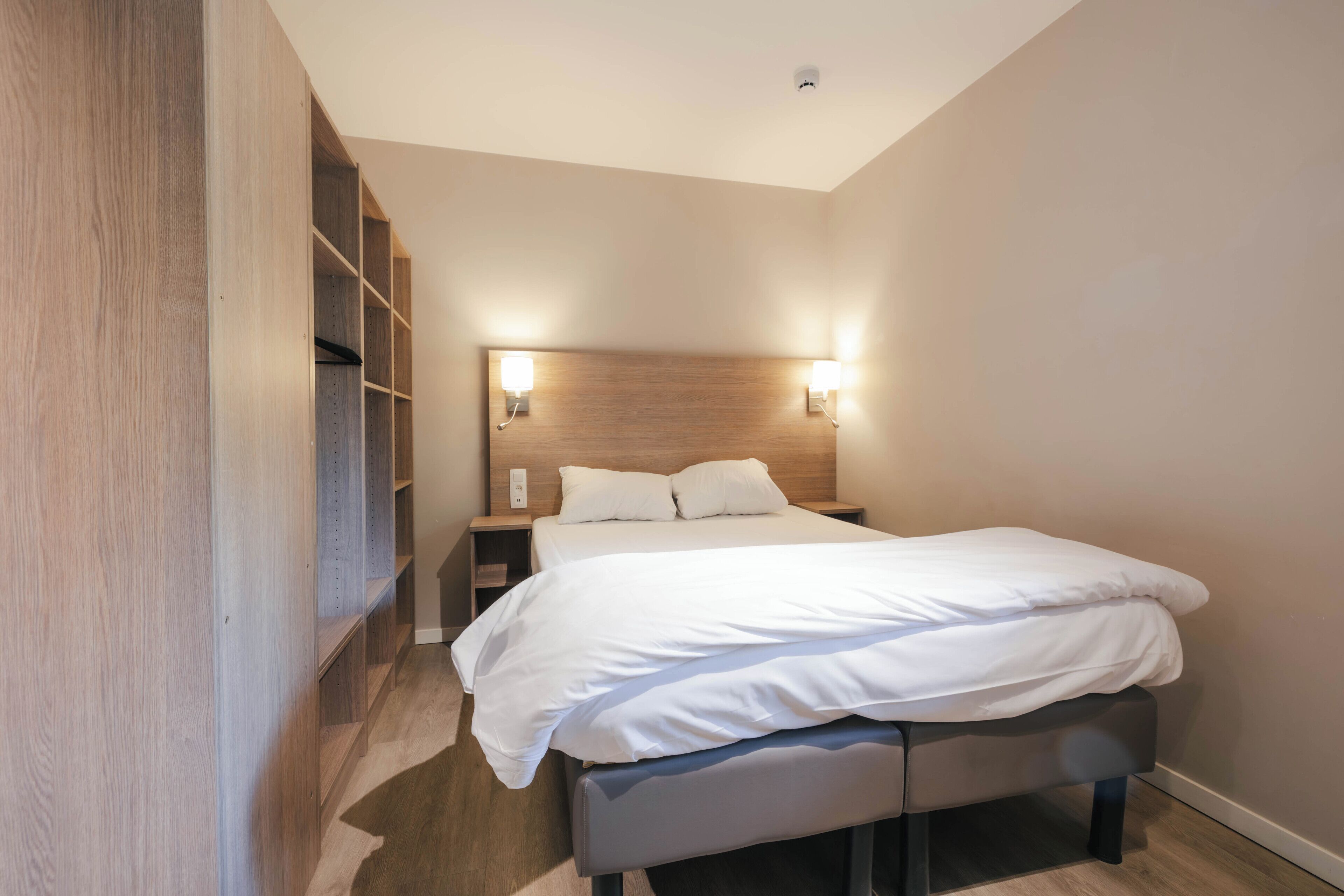 A bedroom with a bed, bedside tables, and built-in shelving.