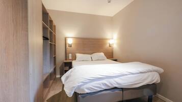 A bedroom with a bed, bedside tables, and built-in shelving.