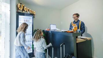 A reception area with a refrigerator stocked with beverages, a computer, and a counter with a phone and a small table.