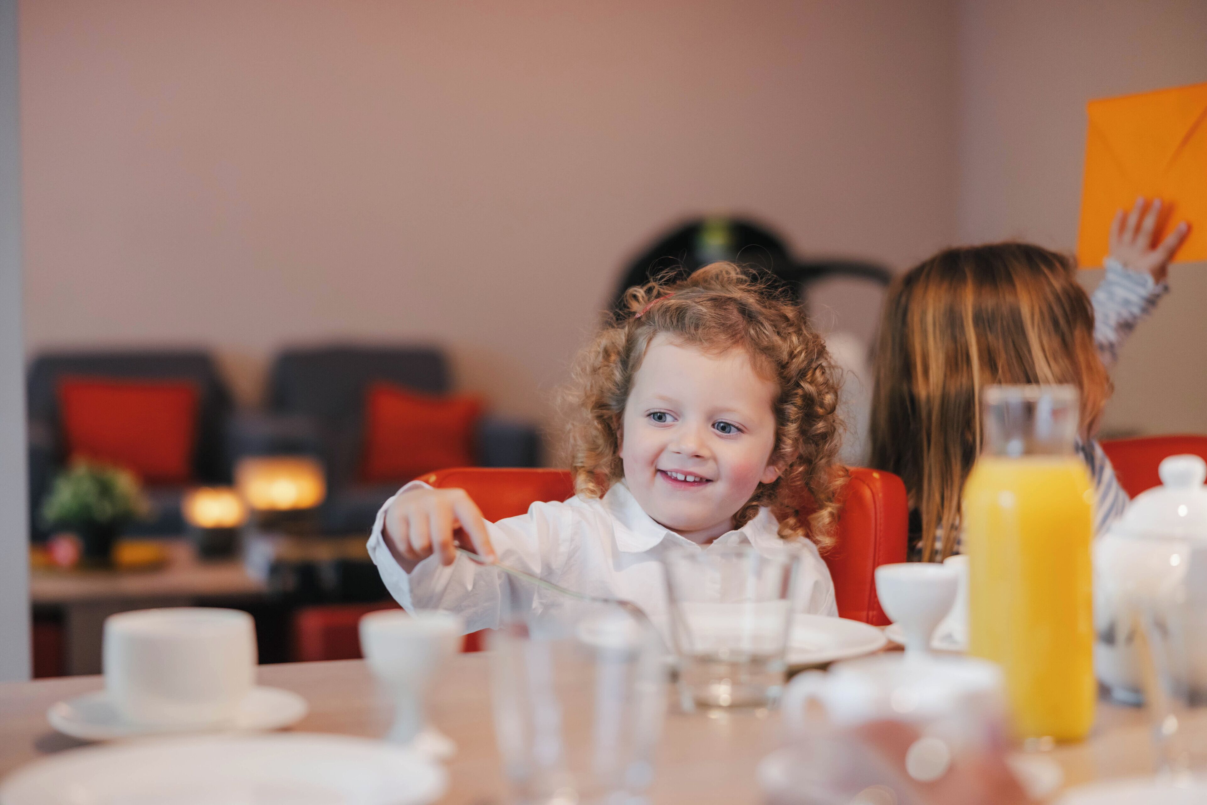 A dining table with plates, cups, and a bottle of orange juice.