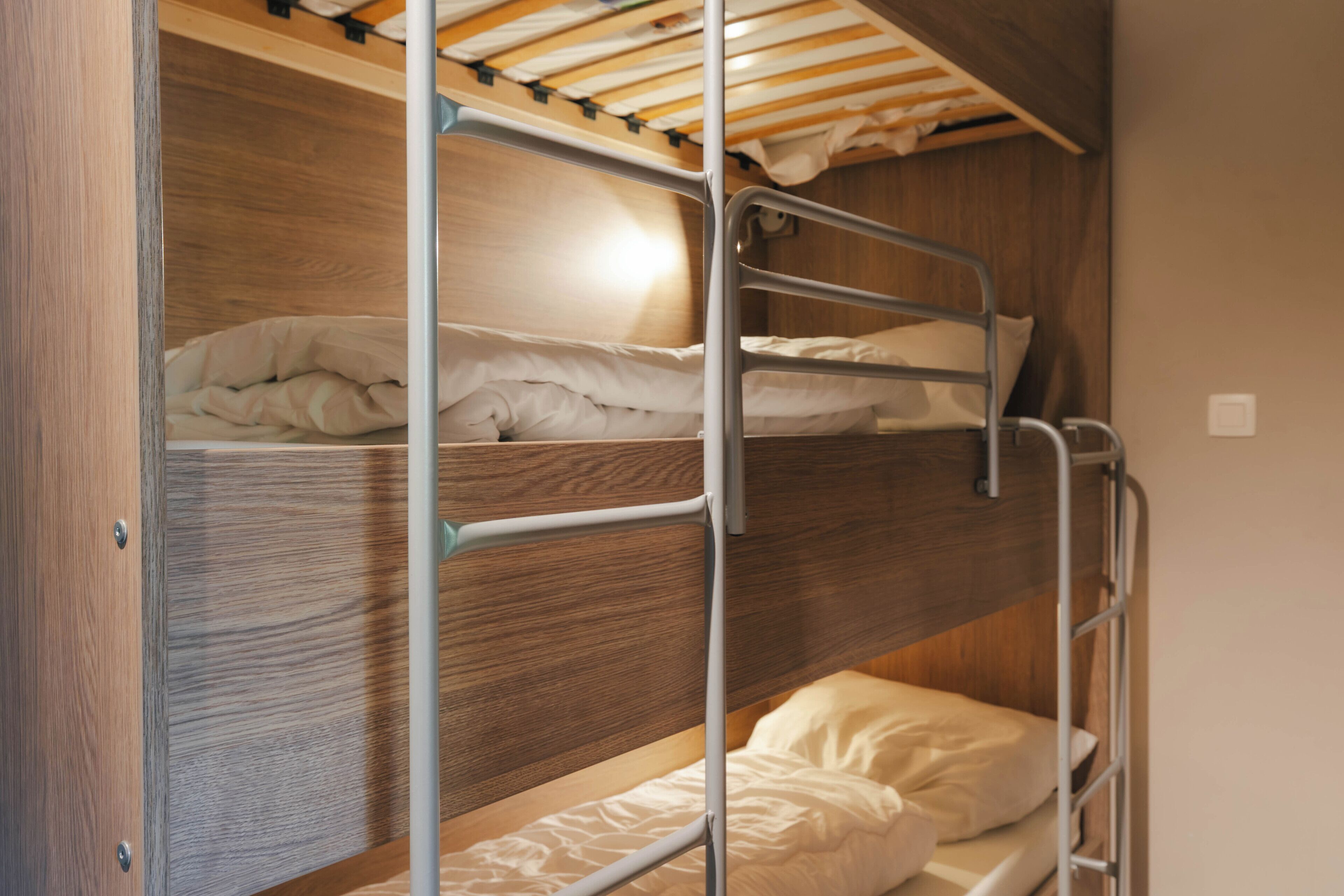 A bunk bed with wooden headboard and metal railings.