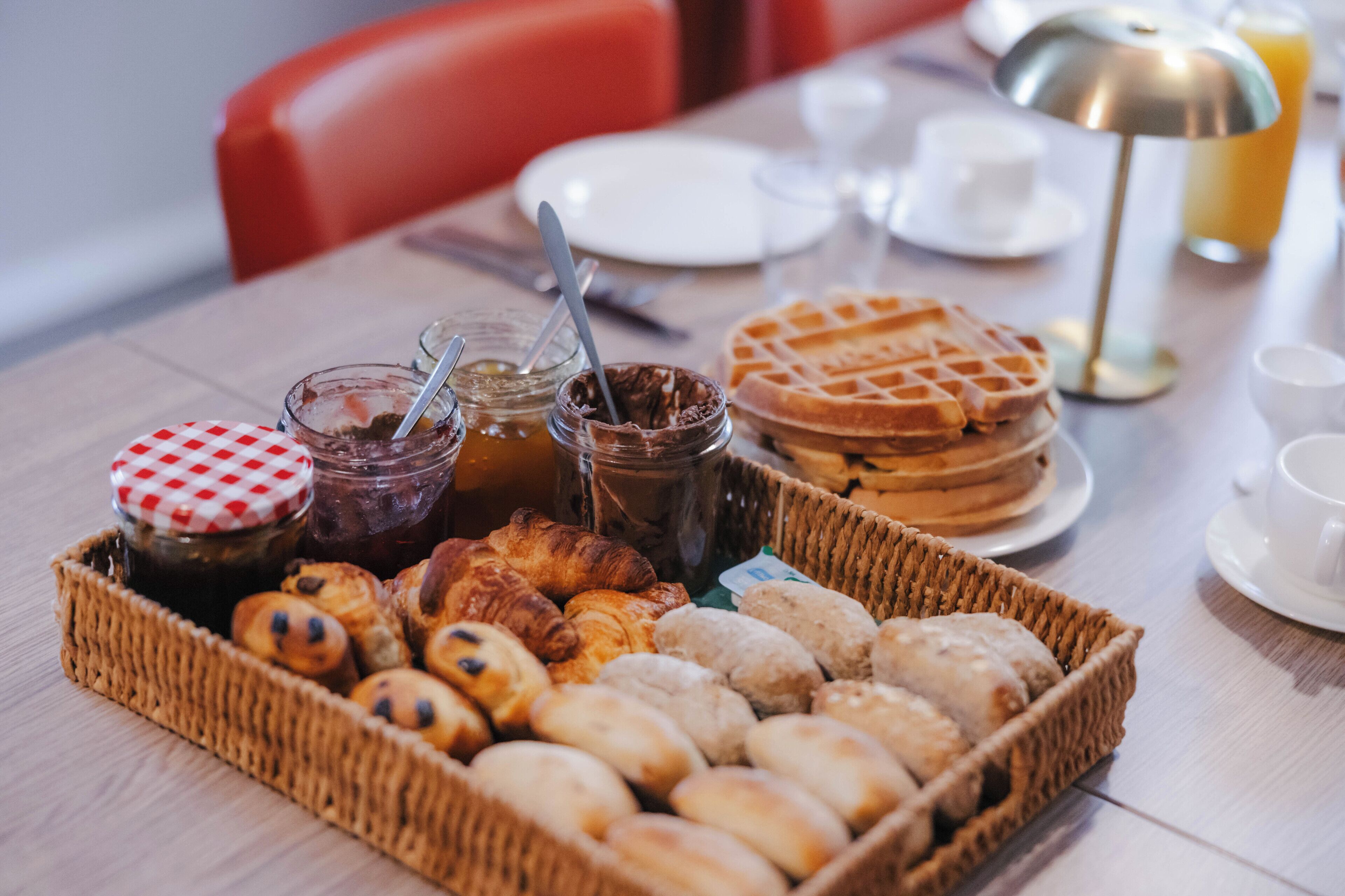 A breakfast buffet with pastries, waffles, and jams.
