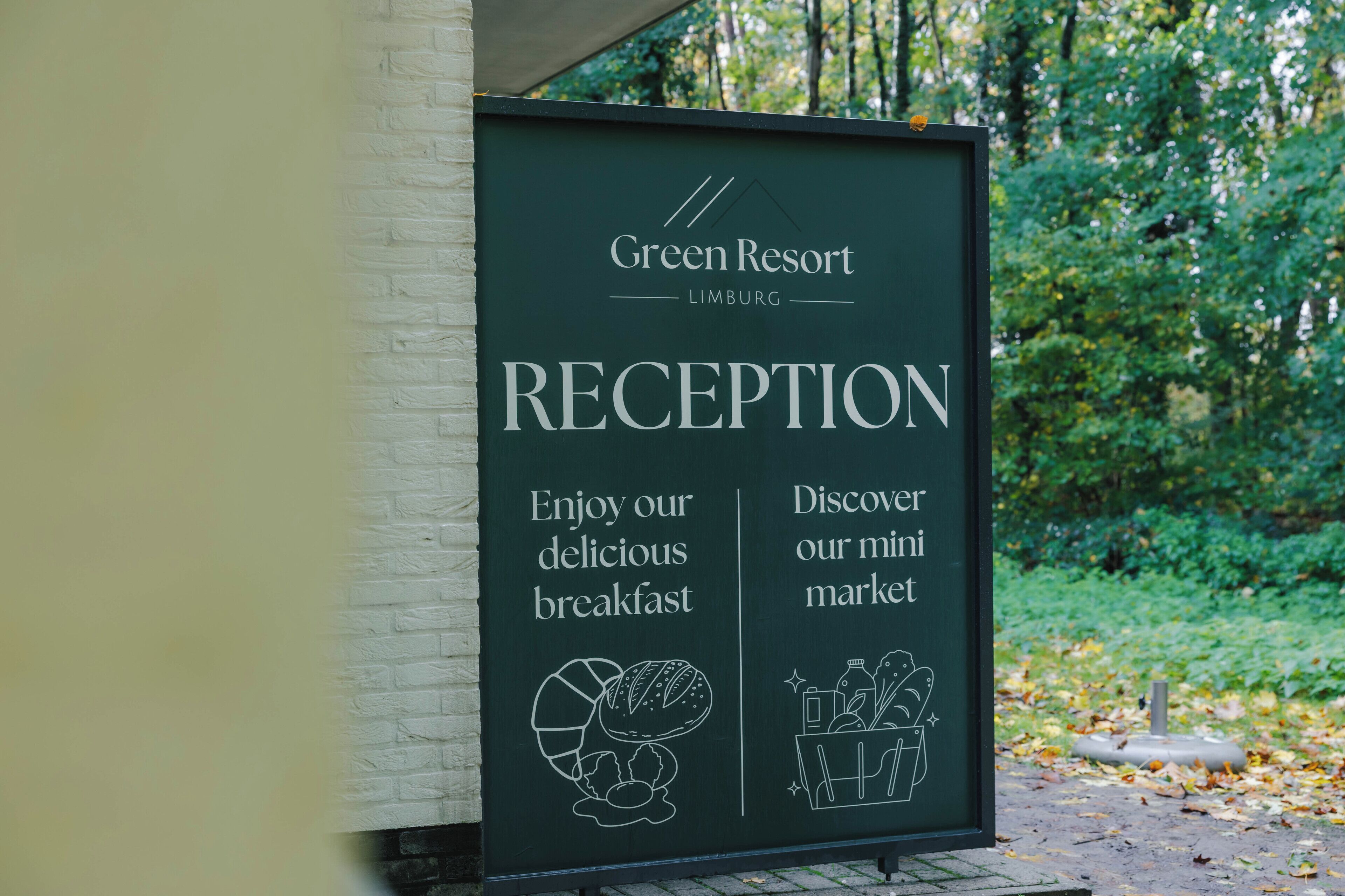 A signboard for Green Resort's reception area, highlighting the breakfast and mini market.