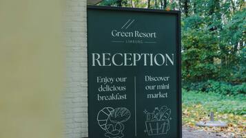 A signboard for Green Resort's reception area, highlighting the breakfast and mini market.