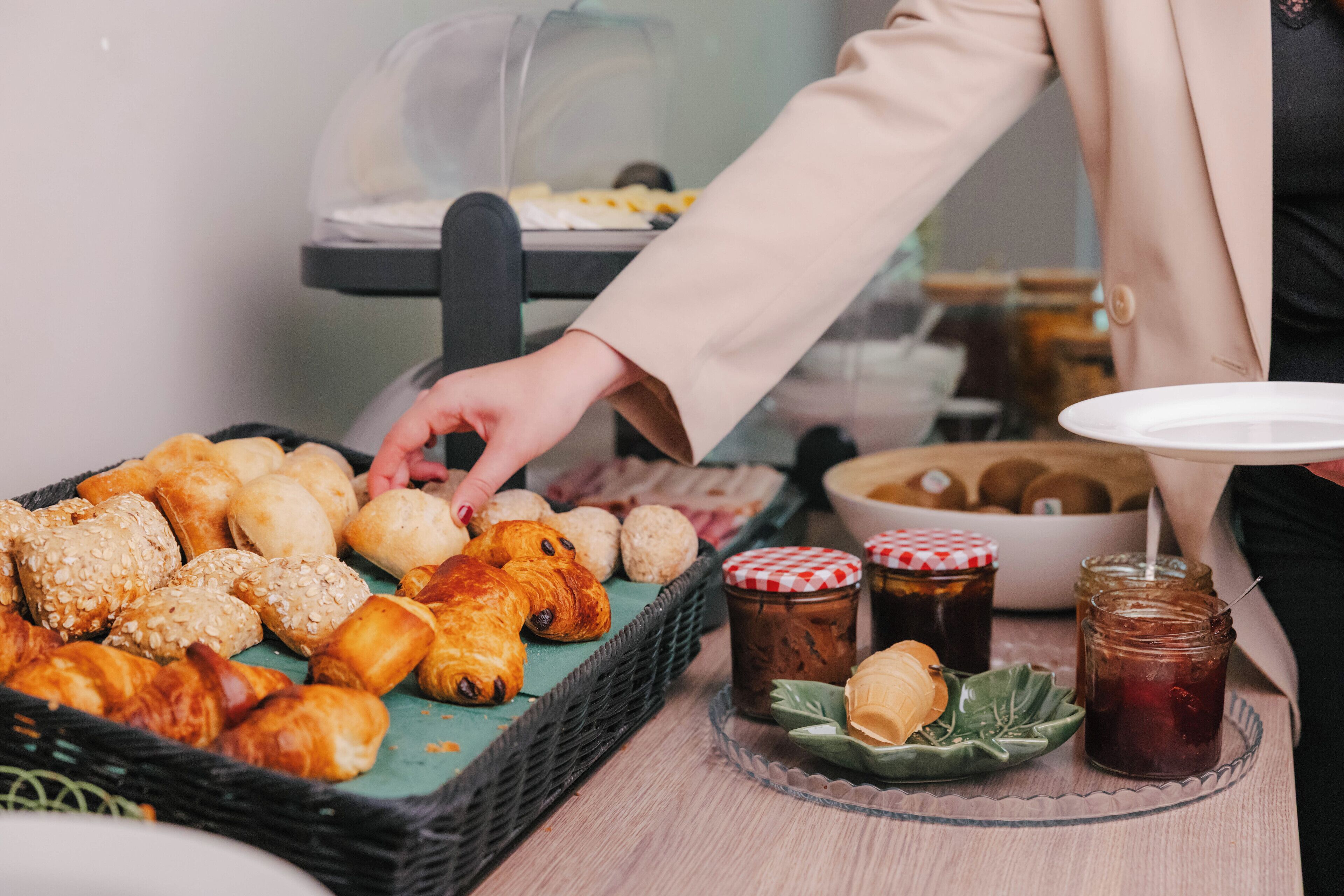 Een buffet met diverse gebakjes, broodjes en potten jam.