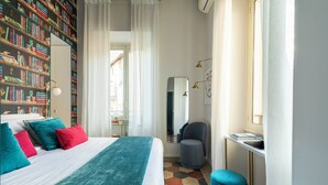 A modern bedroom with a large bed, a bookshelf, a desk, and a chair. - Colosseo book house (Rome)