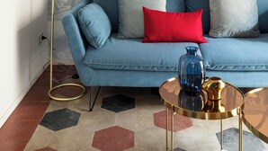 A living room with a blue sofa, a round glass coffee table, and a floor lamp. - Colosseo book house (Rome)