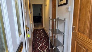 A hallway with a patterned carpet, a metal shelf unit, and wooden doors. - Apartmentsleeps5-parking-garden-petsok (Kelty)