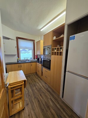 Una cocina compacta con armarios de madera, horno empotrado, microondas y refrigerador.