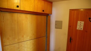 Una stanza con una porta scorrevole in legno, un piccolo quadro elettrico e una porta con un cartello.