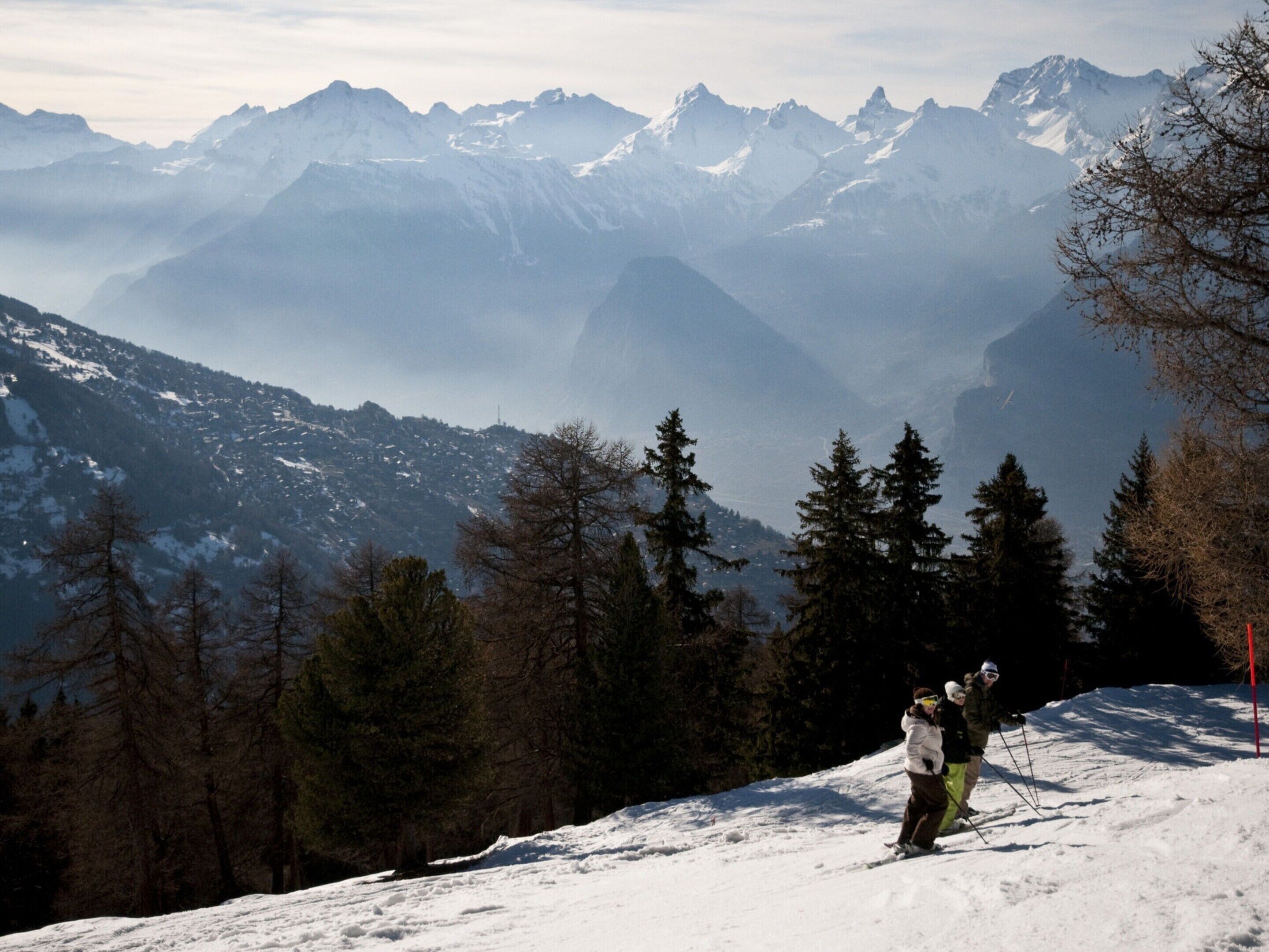 Eine verschneite Berglandschaft, im Vordergrund ein Skifahrer.