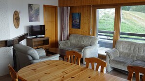 Un accogliente soggiorno con un tavolo di legno, due divani, una televisione e un quadro appeso al muro.