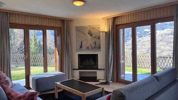 Una sala de estar con chimenea, ventanas amplias y vistas al exterior.