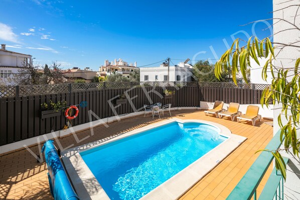 A rectangular swimming pool with a wooden deck, surrounded by a wooden fence, and a clear blue sky above. - Villa Ferragudo (Ferragudo)