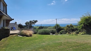 Una propiedad residencial con césped, un árbol grande y vista al mar.