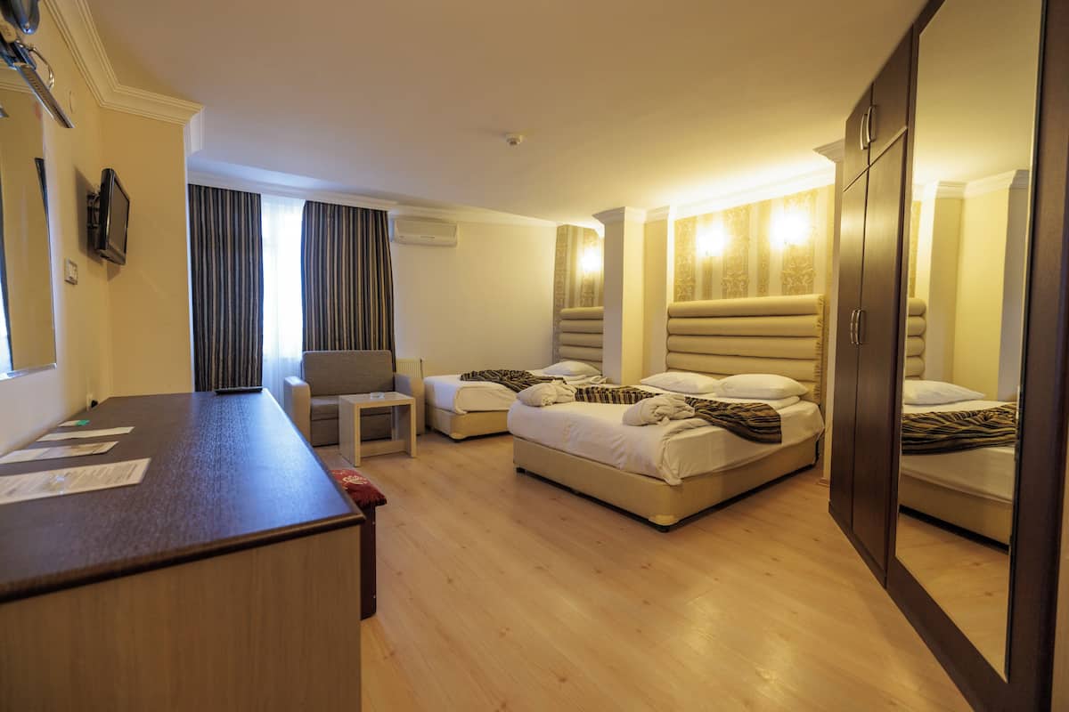 Ein Hotelzimmer mit einem Holztisch, zwei Betten, einem Sessel und einem großen Kleiderschrank.
