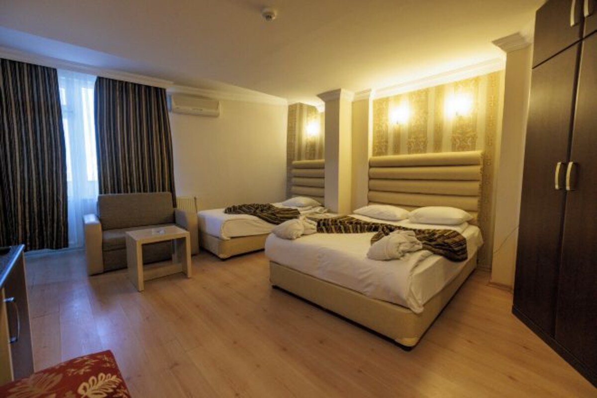 A hotel room with a large bed, a small sofa, a nightstand, and a wardrobe.