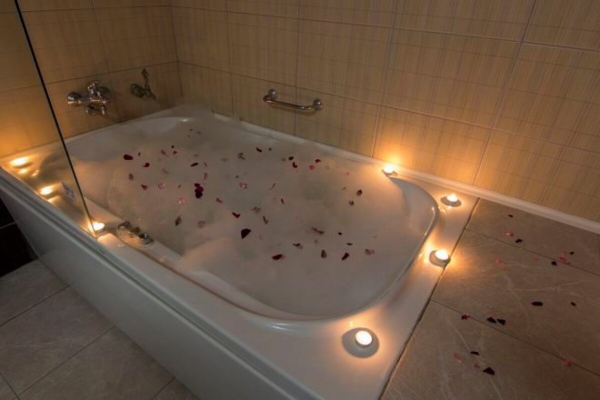 A bathtub with rose petals and candles, suggesting a romantic setting.
