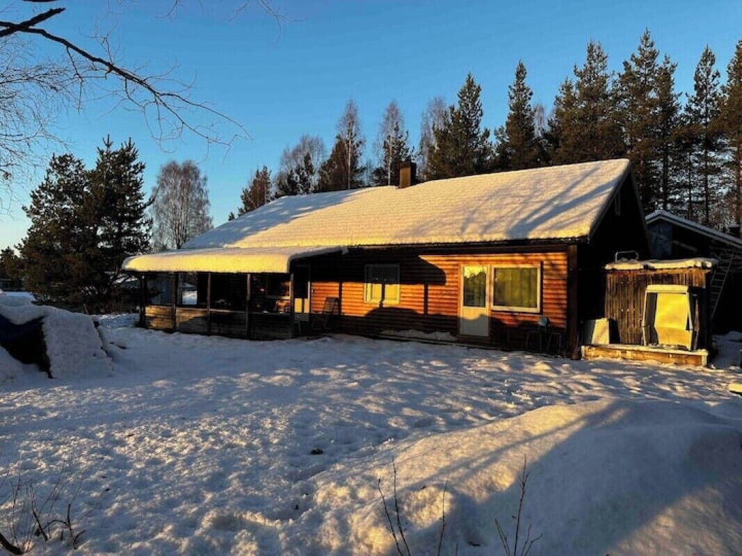Een chalet met een met sneeuw bedekte dak, houten gevel en een overdekte veranda.