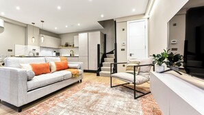 Una sala de estar moderna con un sofá, un sillón y una escalera que sube a un nivel superior.