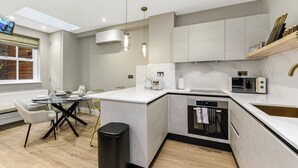 Una cocina moderna con una isla central, electrodomésticos integrados e iluminación colgante.