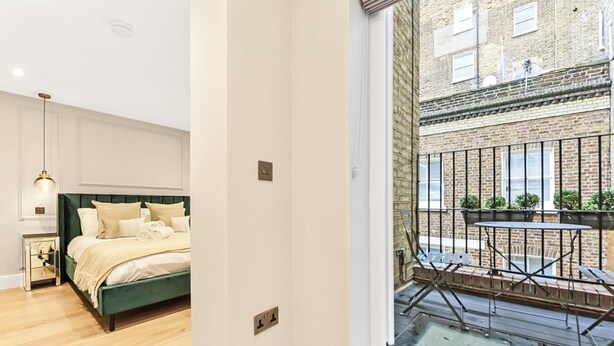 Un dormitorio con una cama verde, una mesita de noche y una lámpara colgante.