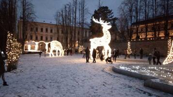 Un patio cubierto de nieve con esculturas iluminadas de renos y un edificio al fondo.