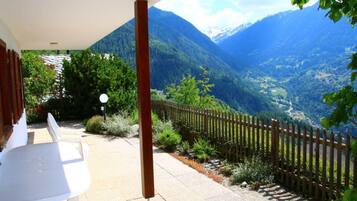 A patio with a view of mountains, a wooden fence, and a white table.