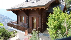 A wooden cabin with a balcony, a satellite dish, and a view of the mountains.