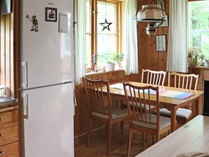 A wooden dining table with chairs, a white refrigerator, and a hanging light fixture. - 4 Star Holiday Home in Kalv (Kalv)