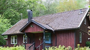 A traditional wooden house with a steeply pitched roof, a chimney, and a porch with a railing. - 4 Star Holiday Home in Kalv (Kalv)