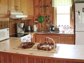 A kitchen with wooden cabinets, a stove, a sink, and various kitchen utensils. - 4 Star Holiday Home in Kalv (Kalv)