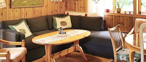 A cozy room with a wooden floor, a sofa, a round wooden table, and a chair.