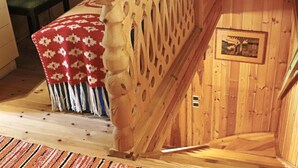 Un intérieur en bois avec un banc, un tapis à motifs et un tableau encadré au mur.