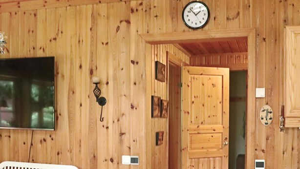 Un intérieur en bois avec une horloge, une porte et un luminaire fixé au mur.