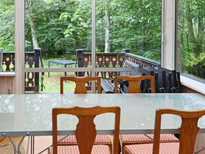 A glass-top table with chairs, a wooden deck, and a view of a forested area. - 4 Star Holiday Home in Kalv (Kalv)