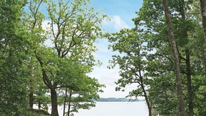 Un parc avec des tables de pique-nique et des bancs, une pelouse et un lac en arrière-plan.