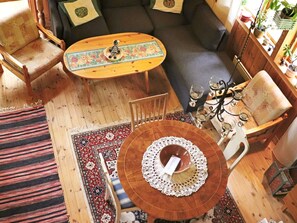 A cozy living room with a wooden floor, a sofa, a coffee table, and a patterned rug.