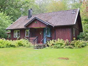 Una casa di legno con tetto spiovente, un camino e un portico con gradini che portano a una porta.