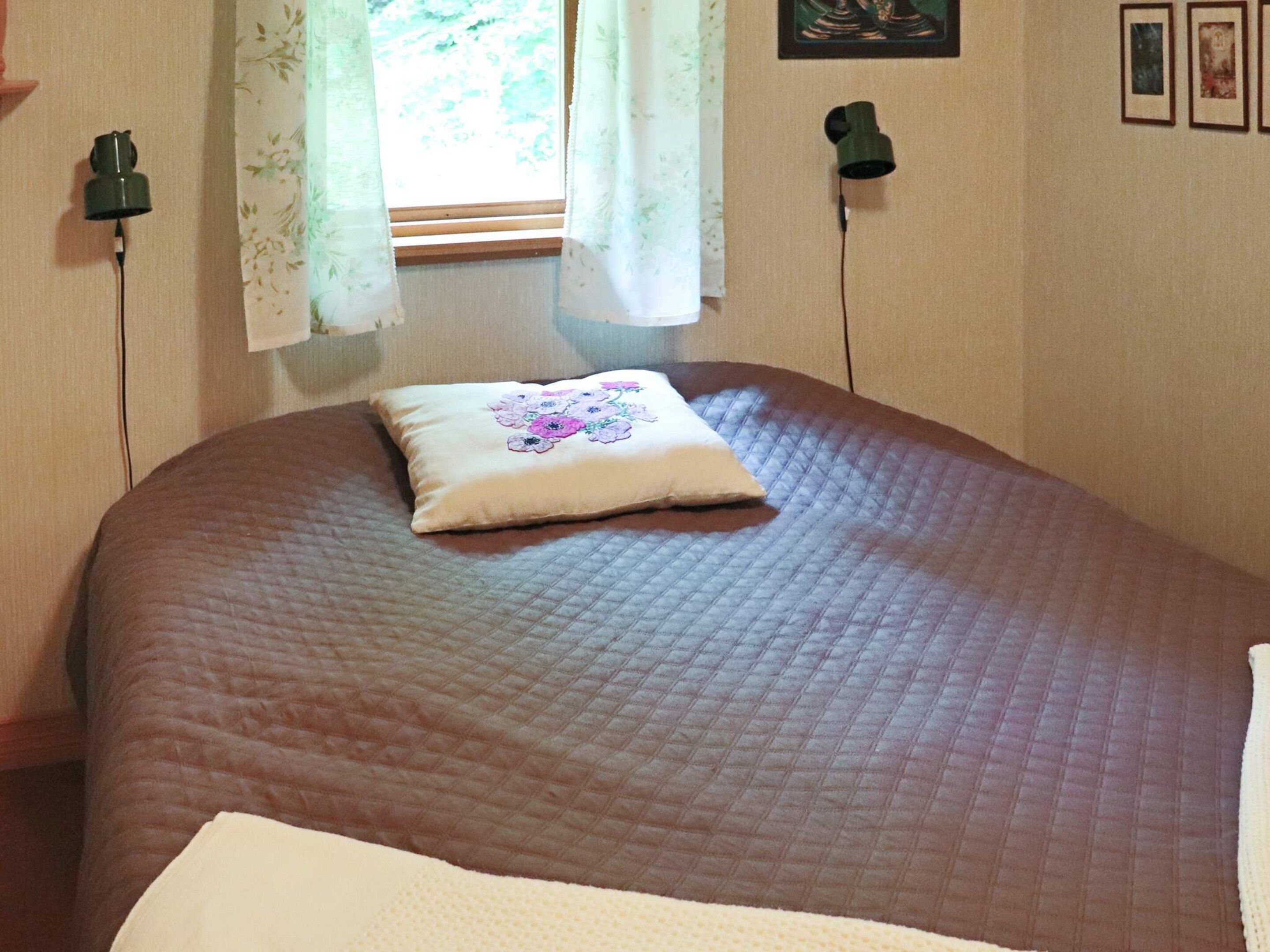 A bed with a quilted brown cover and a decorative pillow.