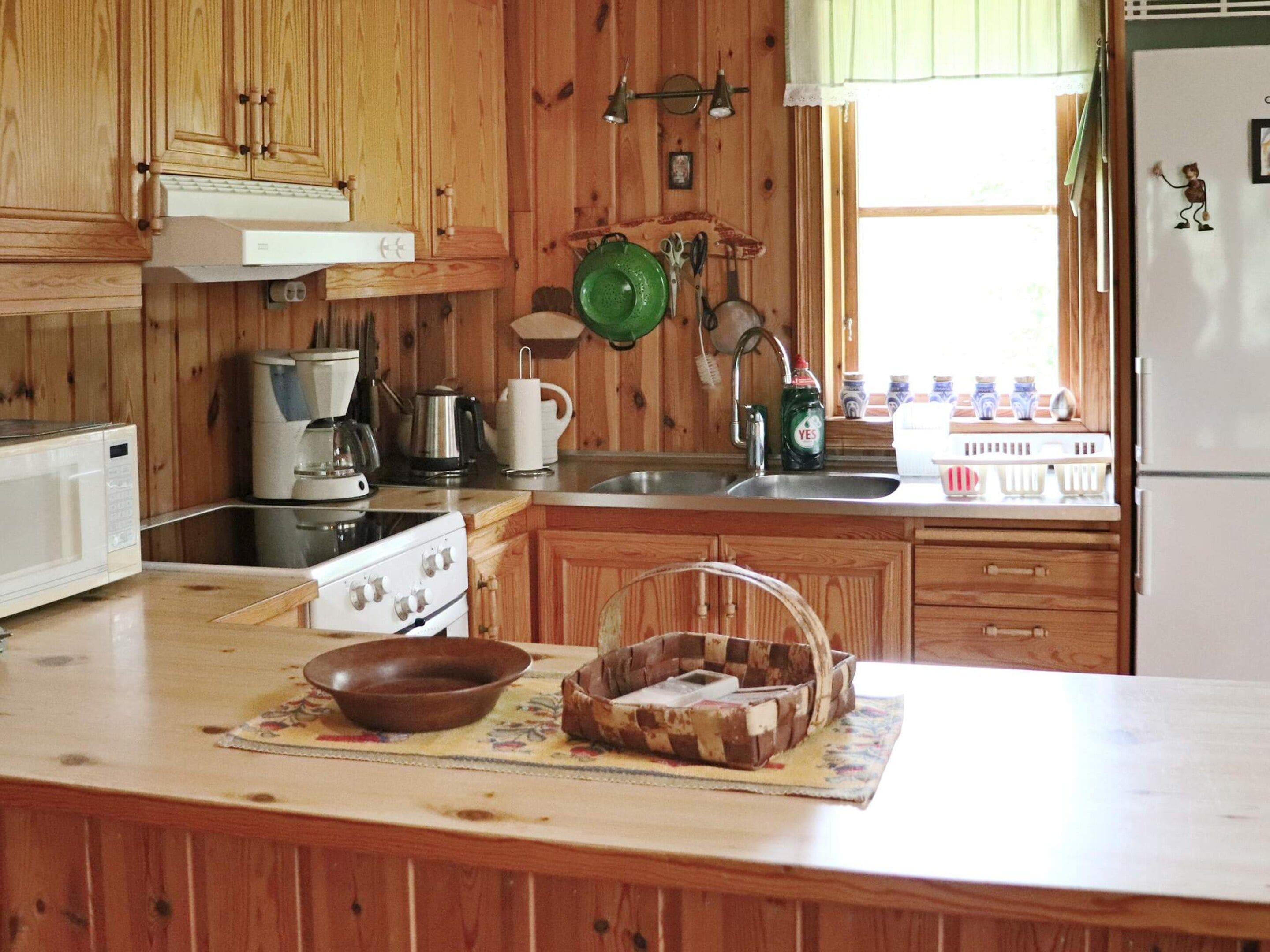 Una cocina con armarios de madera, estufa, pileta y diversos utensilios de cocina.