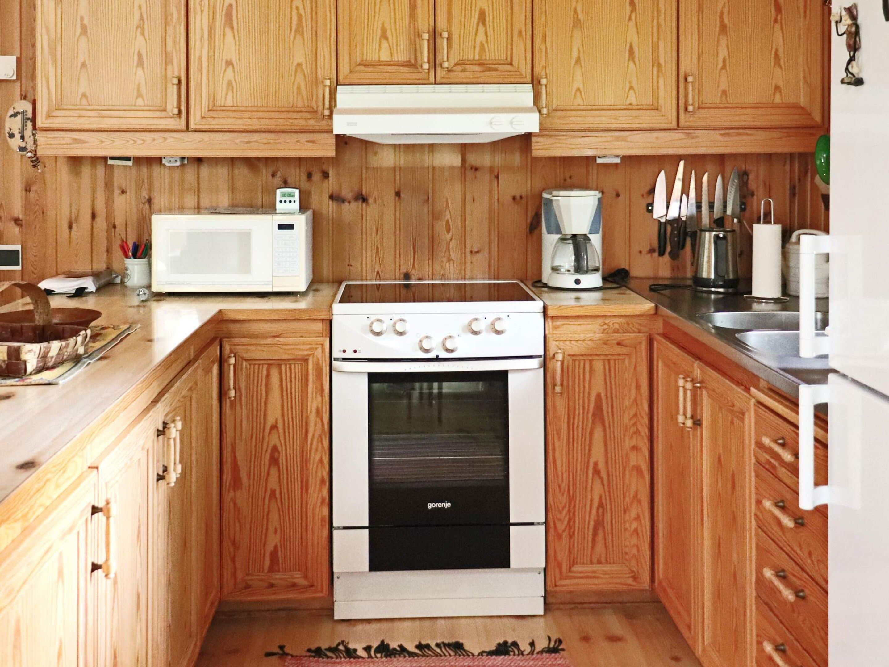 A kitchen with wooden cabinets, a white stove, a microwave, and various kitchen utensils.