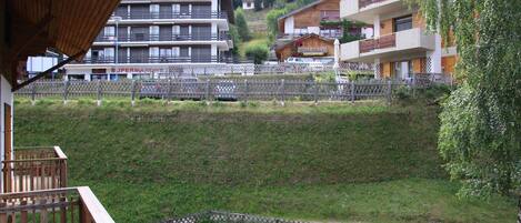 A view of a hillside with buildings, including a multi-story hotel with balconies and a restaurant.