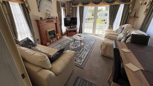 A living room with a sofa, a TV, a fireplace, and a dining area. - 2 Bed Lodge Sleeps 5 - Pet Friendly, Wifi, Parking (Skegness)